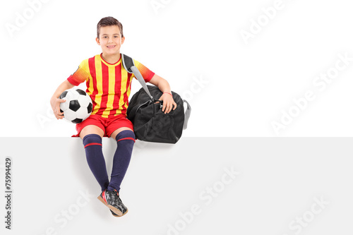 Boy holding a football and sitting on panel