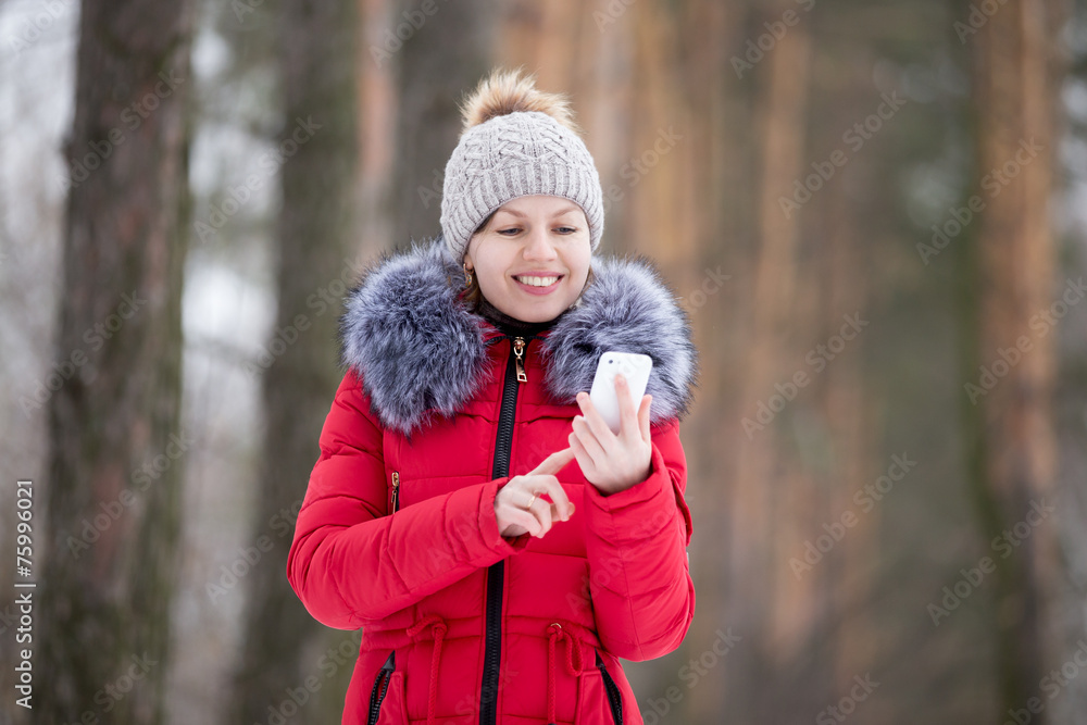 Happy smiling female in red winter jacket with mobile phone, out Happy smiling female in red winter jacket with mobile phone, out