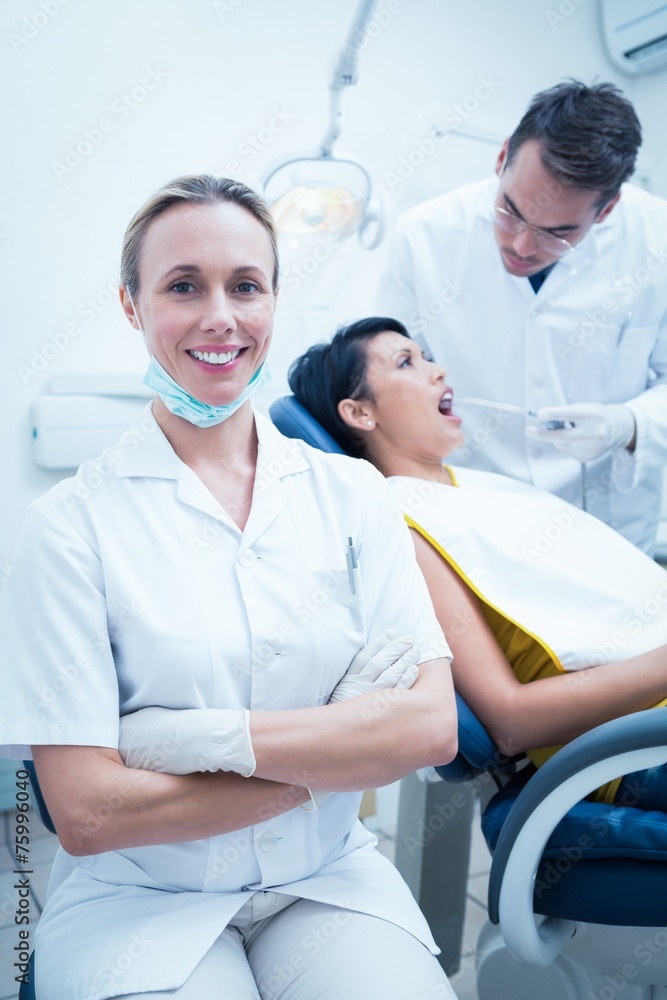 Obraz premium Smiling female dentist with assistant examining womans teeth
