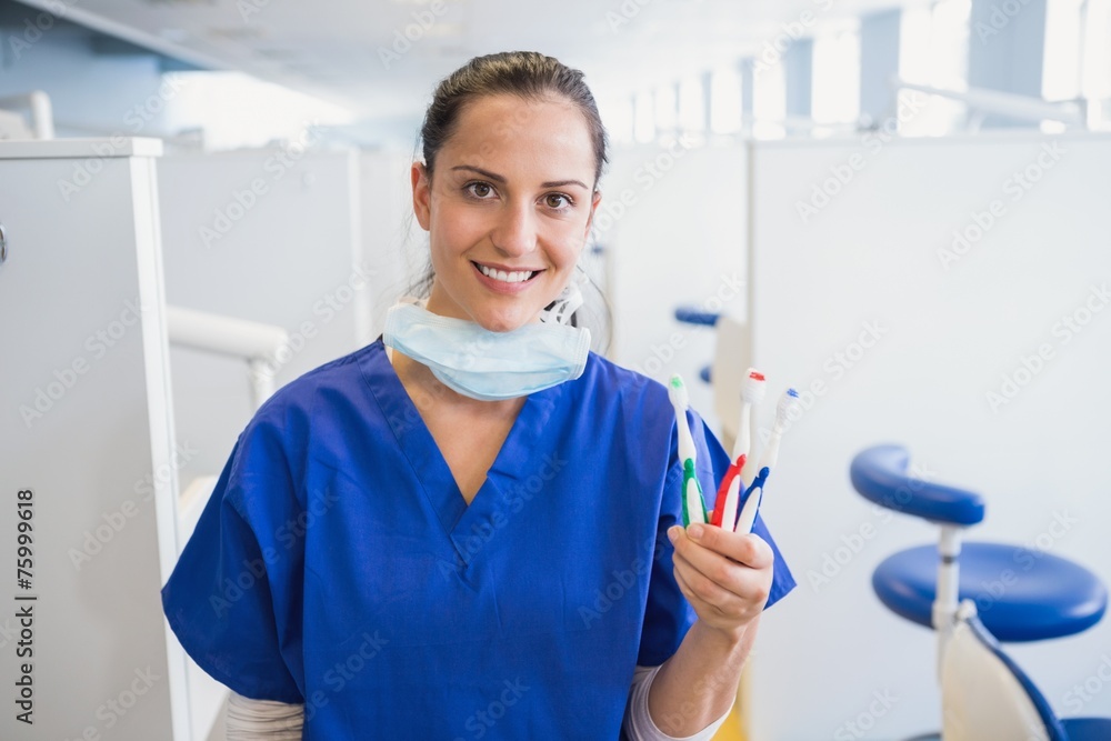 Portrait of a smiling dentist showing toothbrush