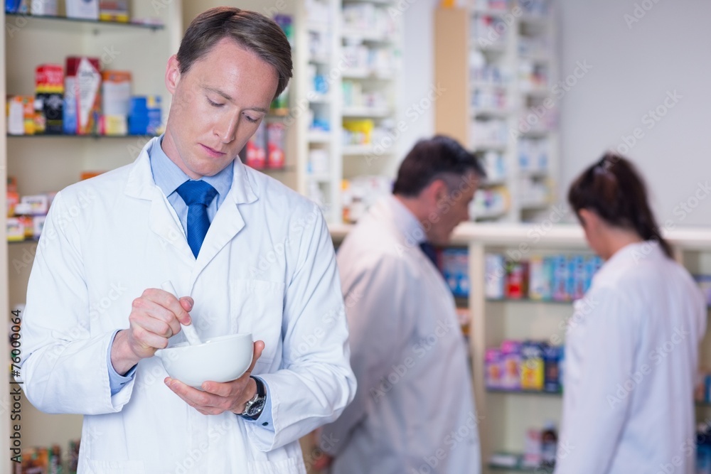 Focused pharmacist using mortar and pestle Focused pharmacist using mortar and pestle