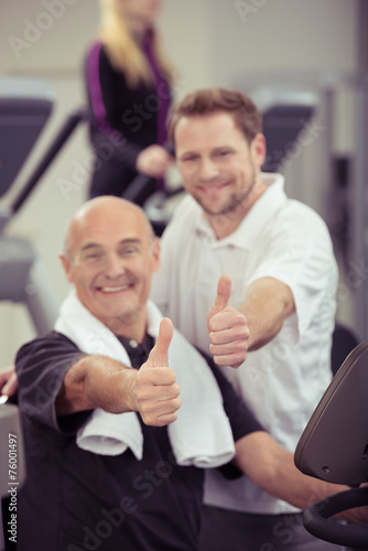 zwei männer im fitness-studio zeigen daumen hoch