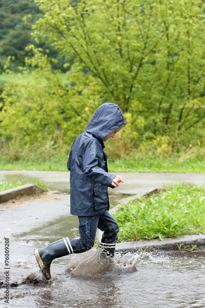 Little boy playing in a puddle