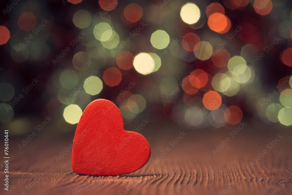 Close up of red heart on old wooden board against defocused ligh Close up of red heart on old wooden board against defocused ligh
