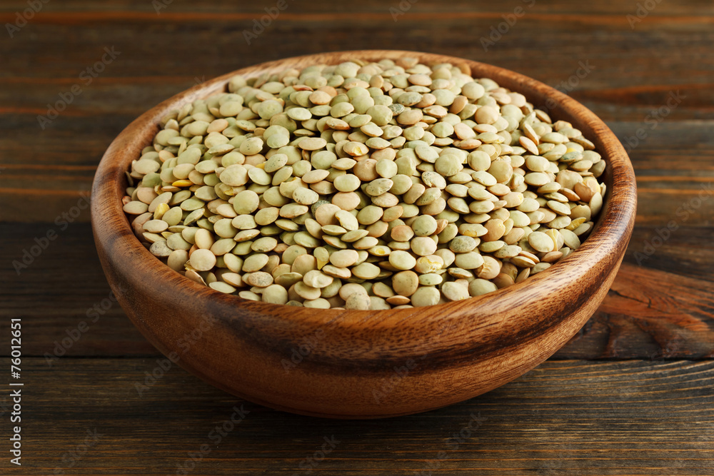 Green lentil in a wooden bowl on wood closeup
