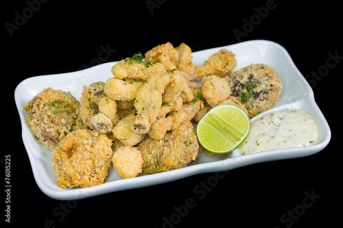 A basket of crispy chicken fingers with platter of vegetables an