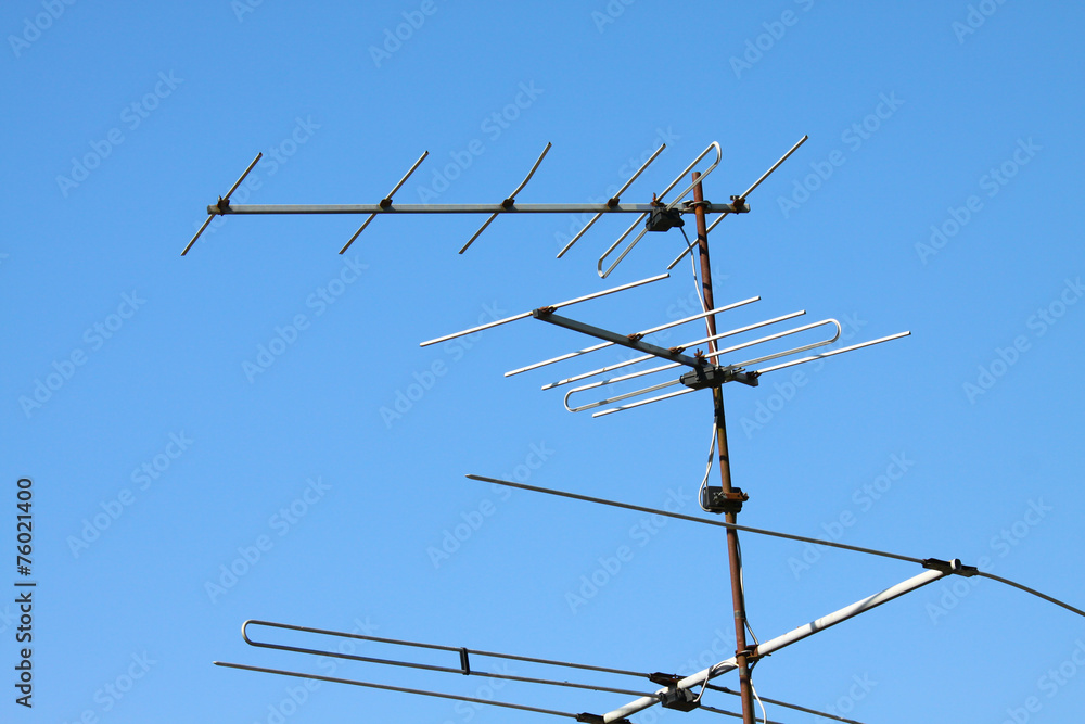 Old TV antenna on house roof with bule sky