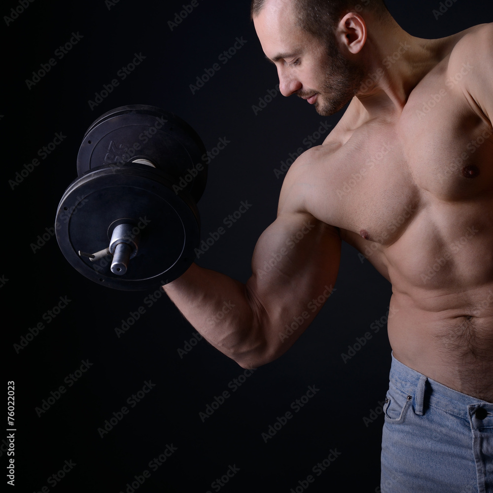 Strong athletic man with perfect body posing with dumbbells Strong athletic man with perfect body posing with dumbbells