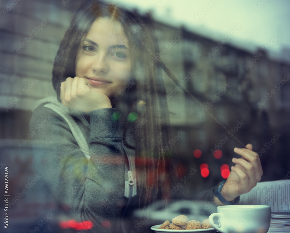 Young woman drinking coffee and reading book sitting indoor in u Young woman drinking coffee and reading book sitting indoor in u