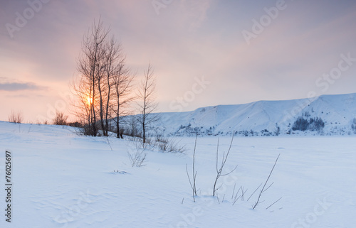 Winter landscape with frozen river and the hilly coast at sunset © Igor Gorshkov