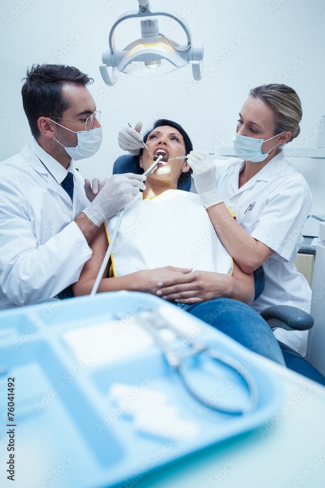 Obraz premium Dentist with assistant examining womans teeth