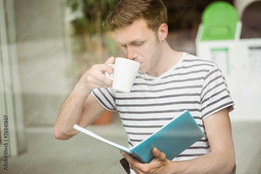 Student drinking a hot drink and holding book Student drinking a hot drink and holding book