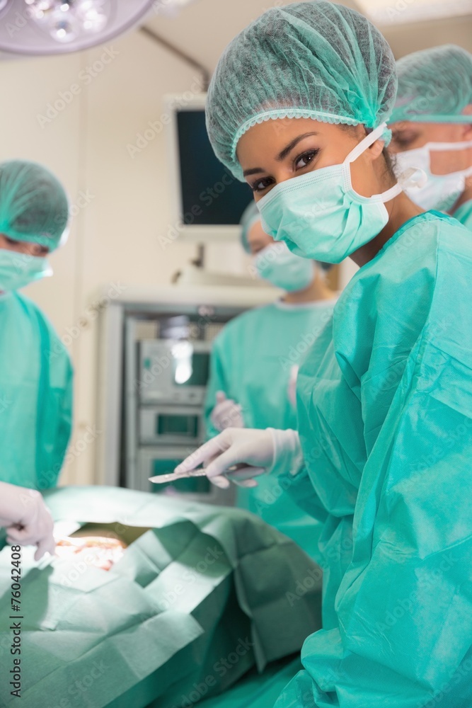 Medical student looking at camera during practice surgery Medical student looking at camera during practice surgery