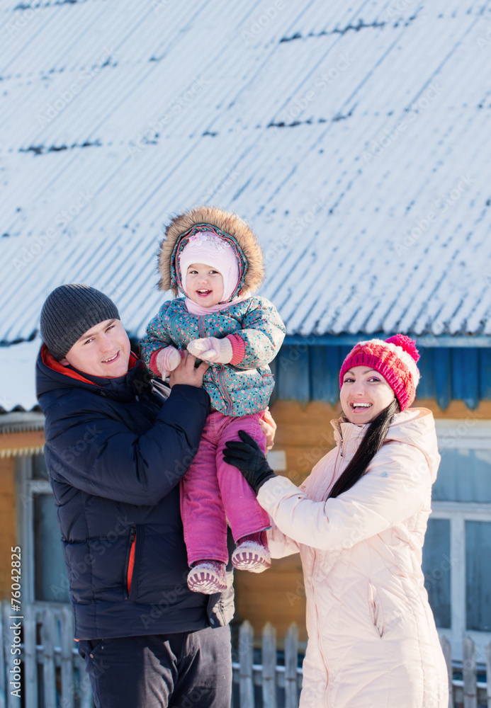 Happy family in warm clothes standing of his house in winter