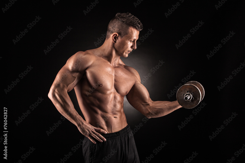 Muscular man with dumbbells on black background