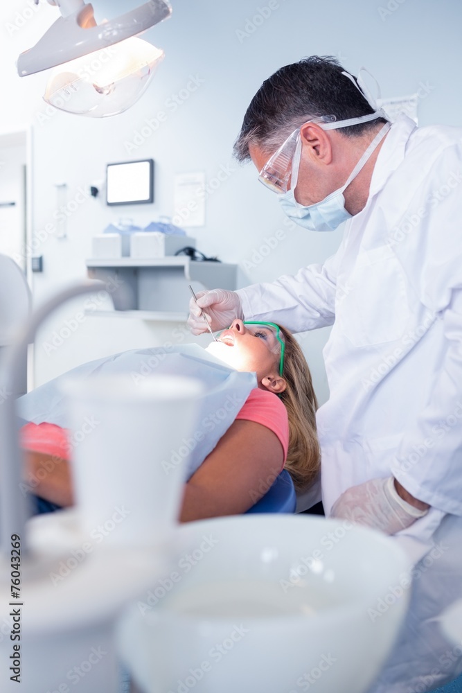 Dentist in surgical mask examining a patients teeth Dentist in surgical mask examining a patients teeth