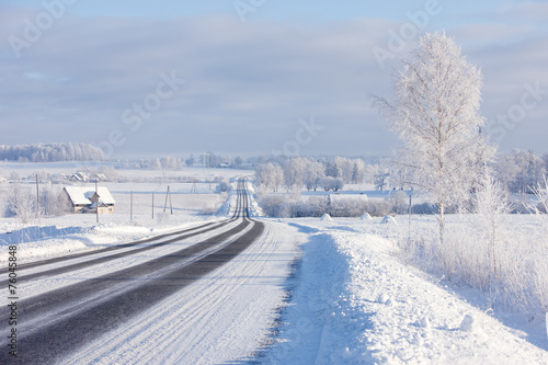 Lines asphalt winter road through rural field on the horizon
