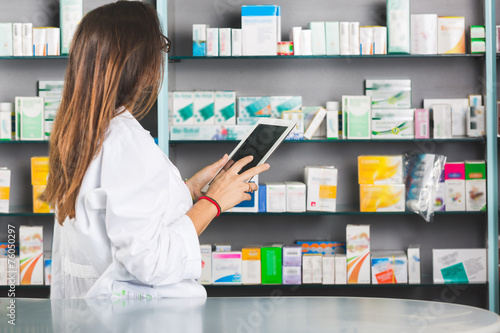 Obraz na plátně Beautiful Pharmacist with Digital Tablet in a Drugstore