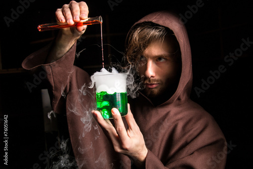 Alchemist in chemical laboratory prepares magical liquids photo