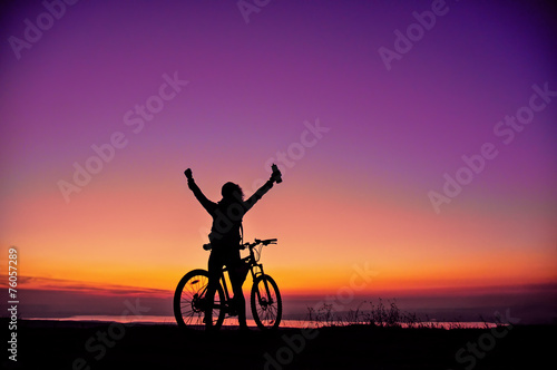 Girl with a bicycle watching the sunset photo