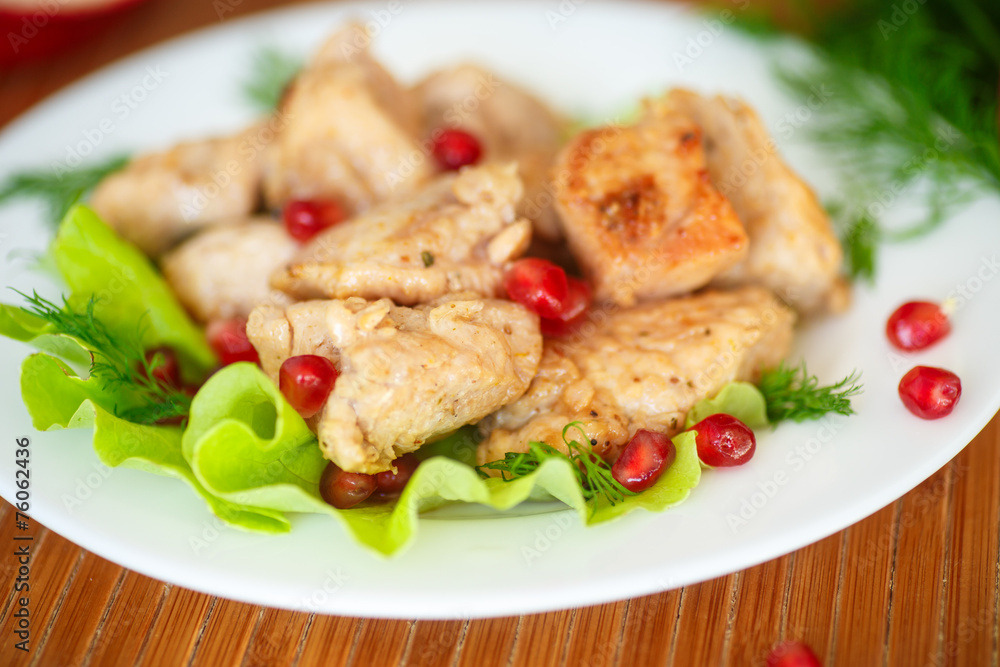 roasted chicken with pomegranate seeds on the salad leaves