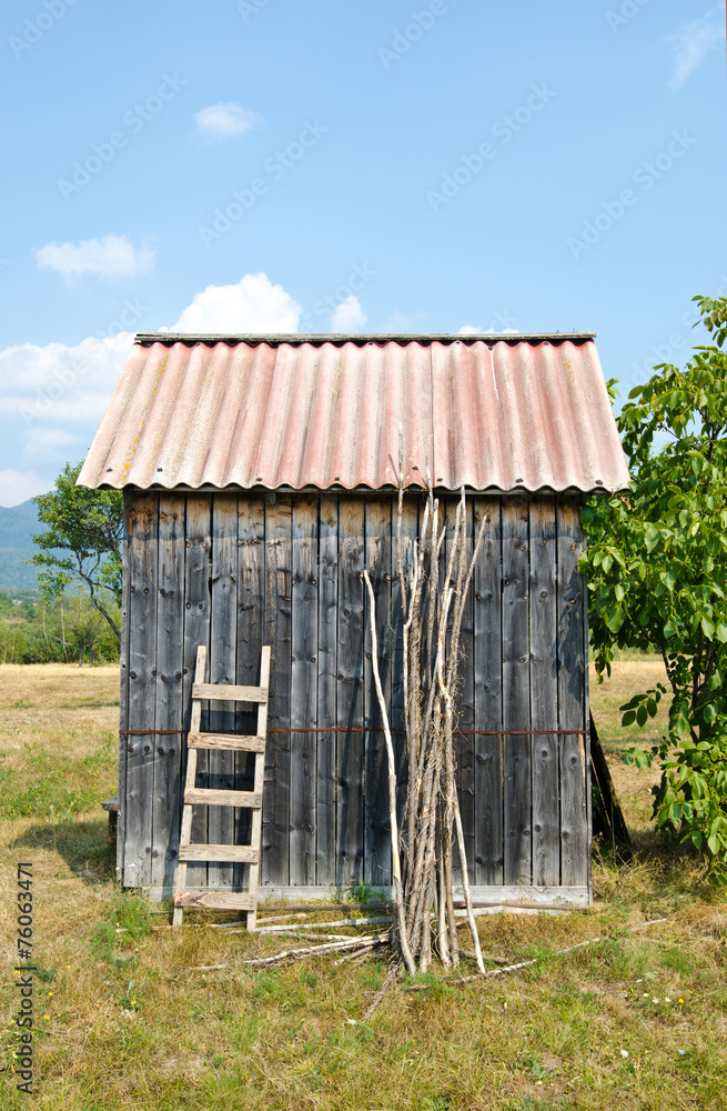 Old shed in a garden.Tiny house with a ladder and wood sticks.