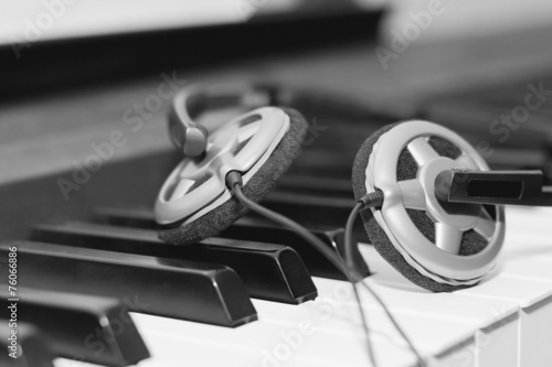 Headphones lying on the piano keys closeup in black and white