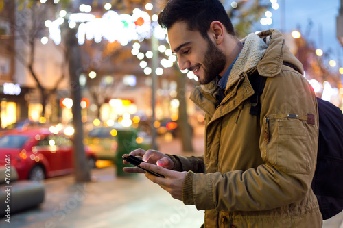Outdoor portrait of young man using his mobile phone at night. photo