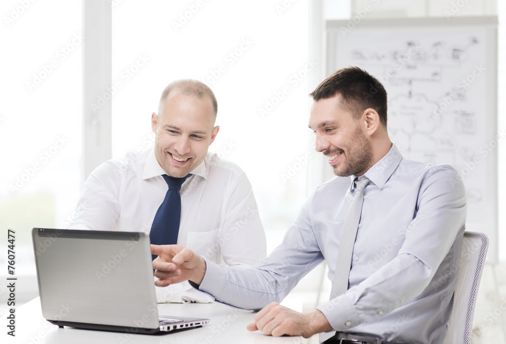 two smiling businessmen with laptop in office two smiling businessmen with laptop in office