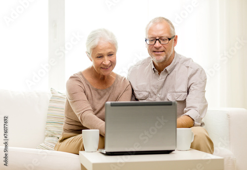 happy senior couple with laptop and cups at home © Syda Productions