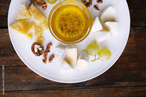 Different sort of cheese with grape, nuts and saucer