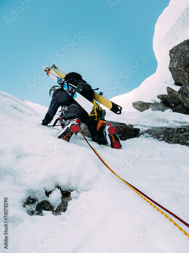 Ice climbing: mountaineer on a mixed route of snow and rock duri