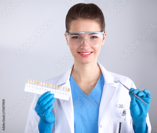Attractive female dentist with tools   standing on gay