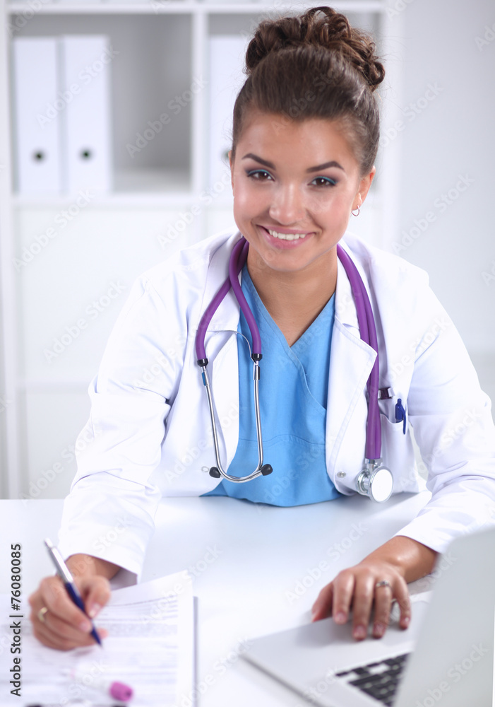 Female doctor sitting on the desk and working a laptop in Female doctor sitting on the desk and working a laptop in