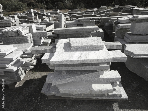 Stacks of granite slabs in a yard under sunlight