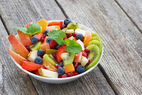 Fruit and berry salad on wooden table, horizontal