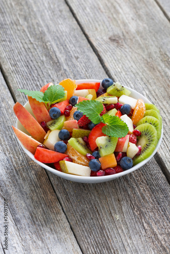 Fruit and berry salad on wooden table, vertical