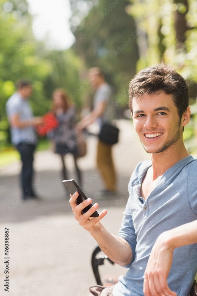 Handsome student sending a text outside