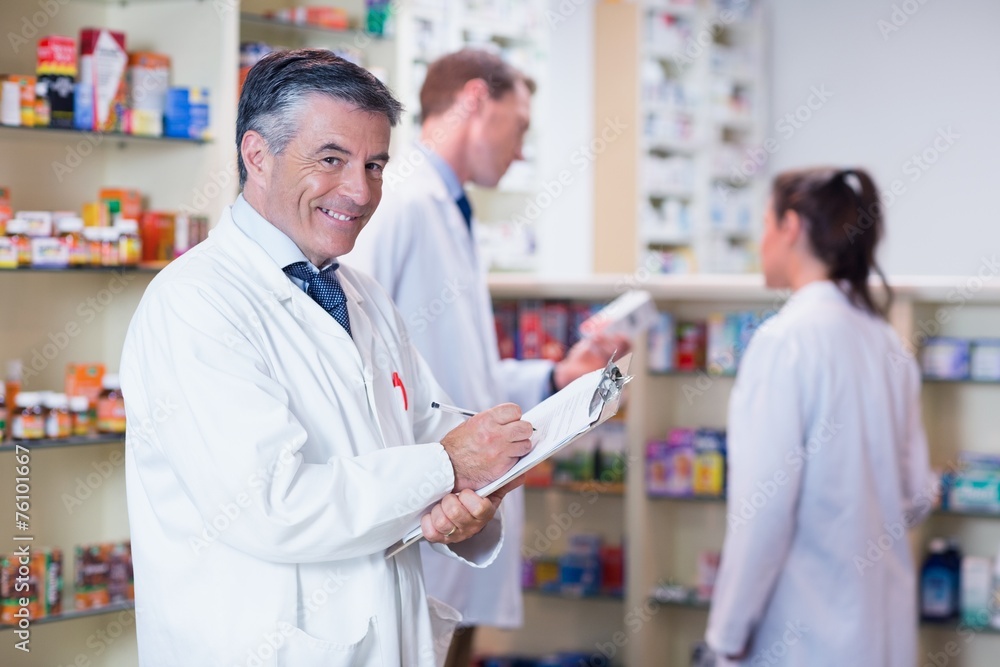 Smiling pharmacist in lab coat writing a prescription Smiling pharmacist in lab coat writing a prescription