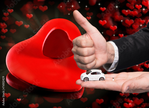 Businessman in black suit holding two small car model photo