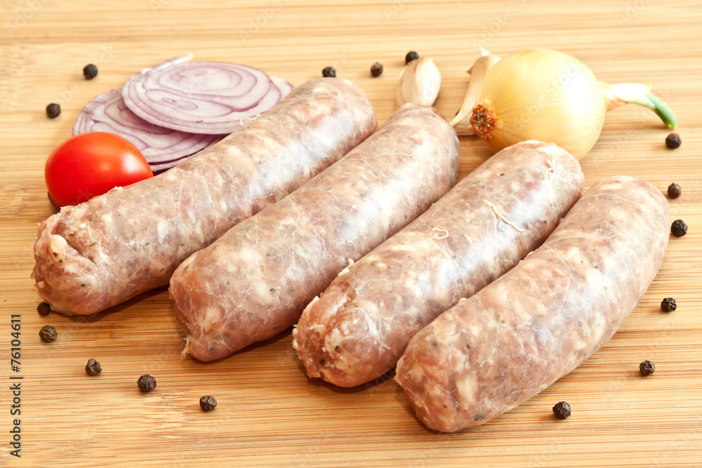 Uncooked sausages with vegetables on the chopping board Uncooked sausages with vegetables on the chopping board