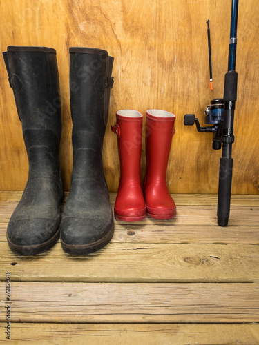 mans and boys rubber boots with  fishing rod