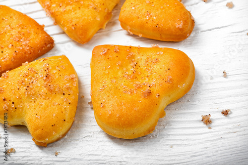 Heart-shaped biscuit on wooden background.