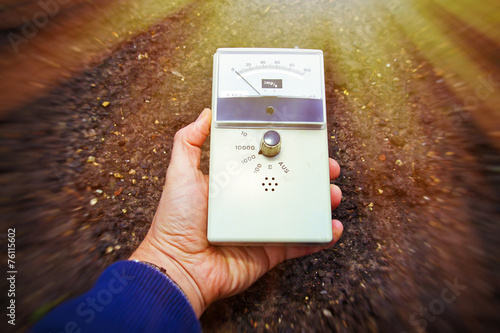 Mann mit Geigerzähler misst radioaktive Strahlung photo