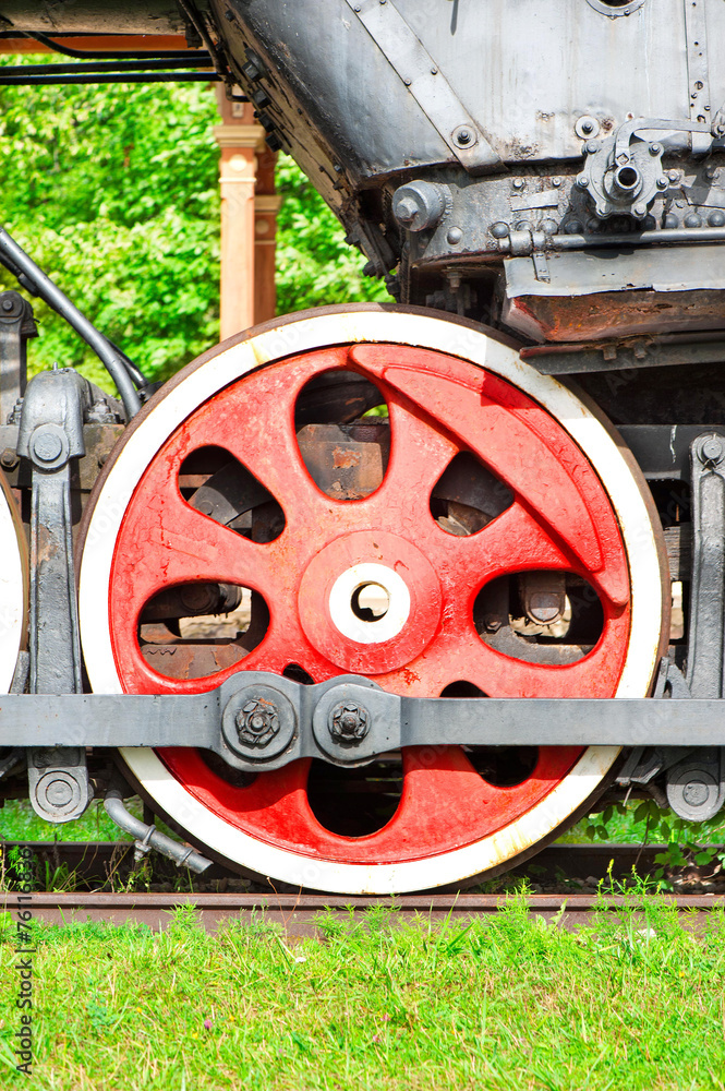 Red iron wheel of old steam locomotive. Outdoors closeup.