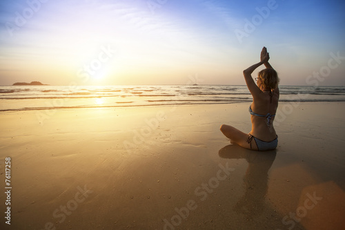 Girl sit at the seaside and meditating in yoga pose.