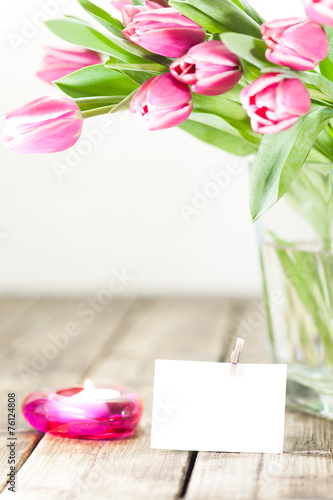 Purple tulips in a Vase on old wooden table to a candle burns