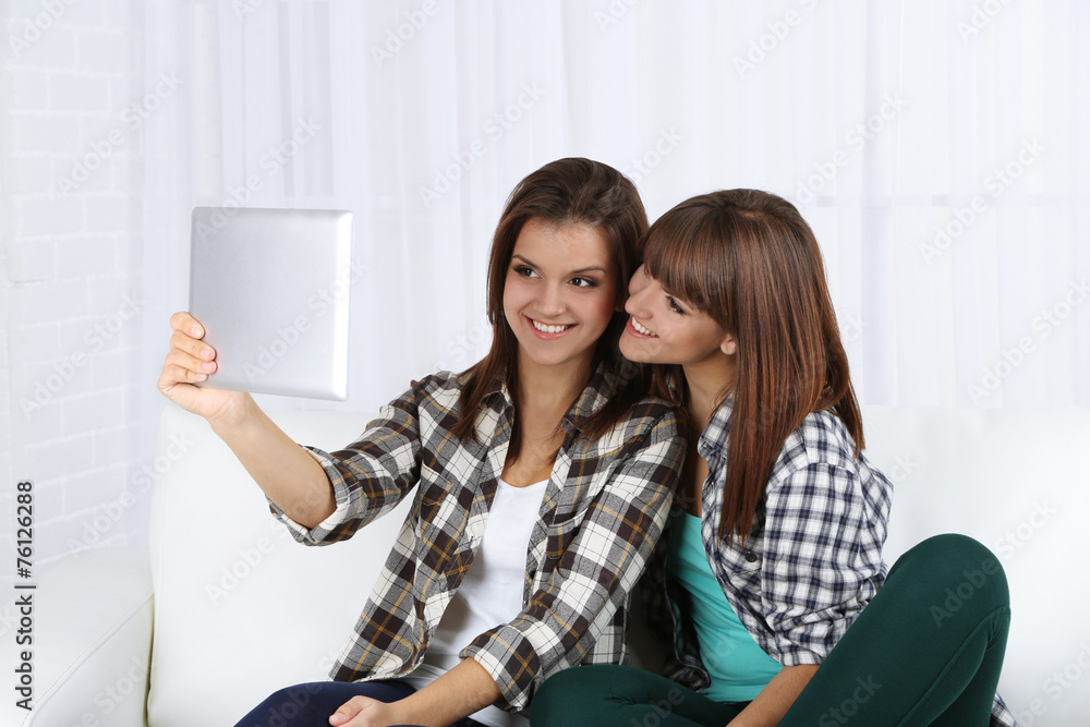 Beautiful girls twins with electronic tablet on sofa Beautiful girls twins with electronic tablet on sofa