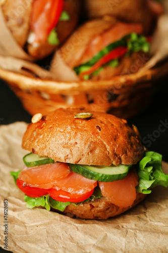 Sandwiches with salmon and vegetables on wooden background