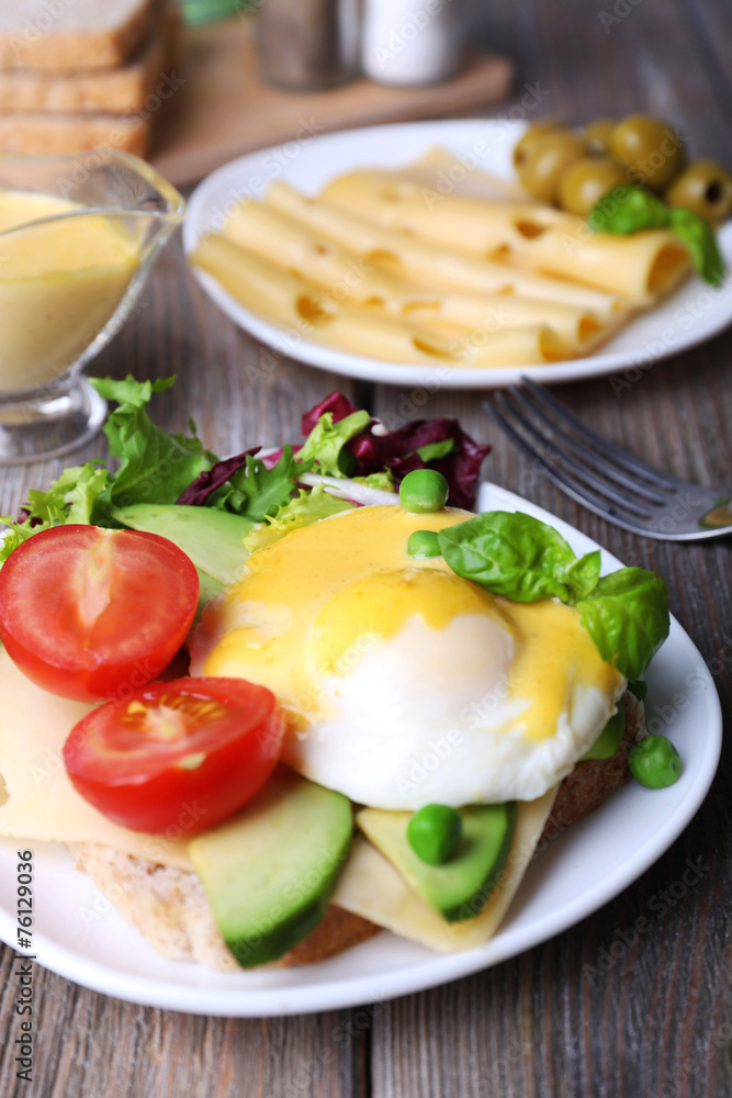 Toast with egg Benedict and avocado on plate on wooden table Toast with egg Benedict and avocado on plate on wooden table
